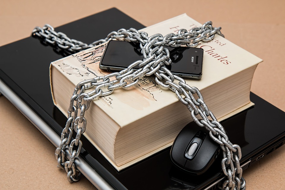 Laptop, book, phone and mouse with chains around them